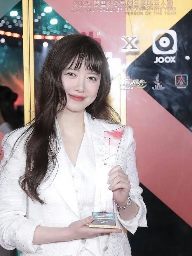 people-woman-holding award-white blazer-long dark hair-smiling