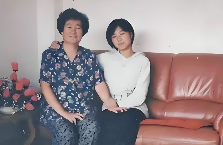 people-Two individuals (likely two women)-sitting-A-red leather couch-A-white wall-B-floral print shirt-C-white hoodie