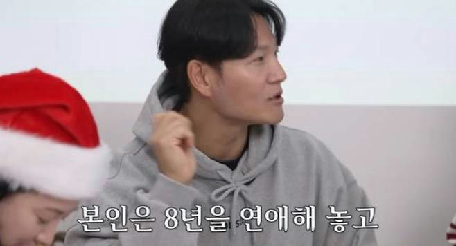 people-Man in a grey hoodie talking-A-Woman wearing a Santa hat (partially visible)-B-Korean subtitles visible at the bottom-C