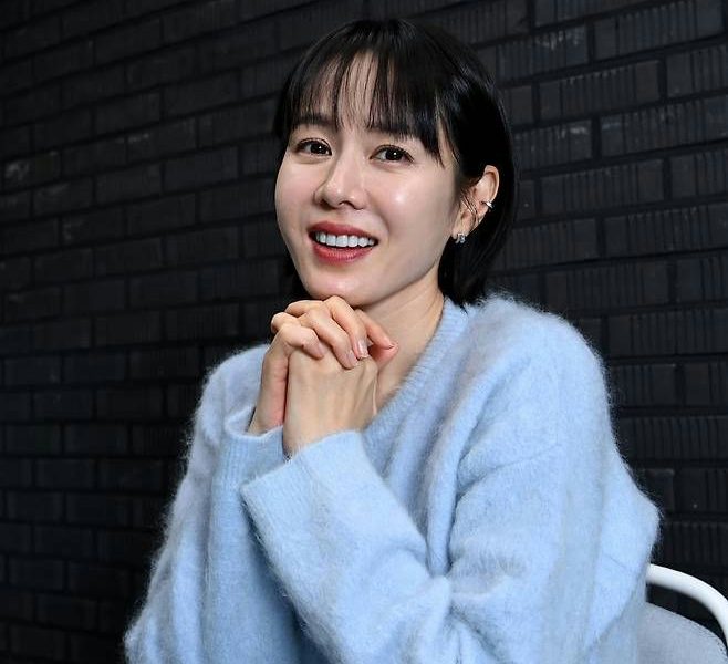 people-woman-A-smiling-A-short black hair-A-light blue fuzzy sweater-A-hands clasped