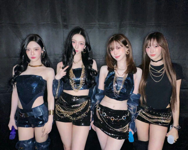 people-four women-A-K-pop style-A-black and blue outfits-A-sequins and chains-B-stage or backstage setting-C-dark background