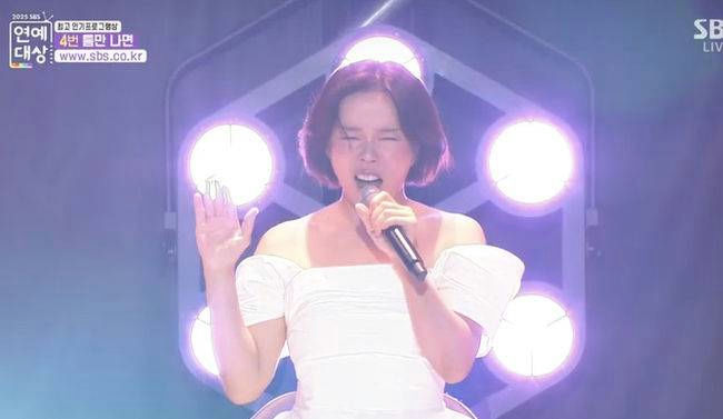 people-One woman-A-singing-A-white off-shoulder dress-A-microphone-A-stage lighting-A-short brown hair
