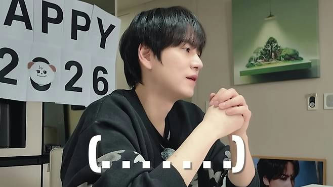 people-One male-A-black hair-A-black sweatshirt-A-looking right-A-hands clasped-A-text overlay (....)-A-Happy 2026 sign
