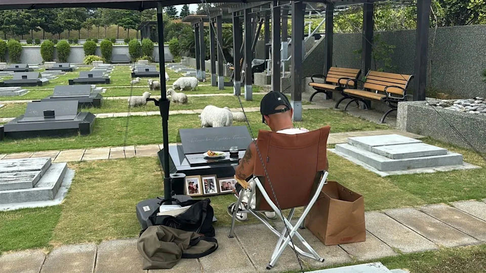people-1-man-A-cemetery-A-graves-A-sheep-statues-A-folding-chair-A-memorial-A-food-A-photographs