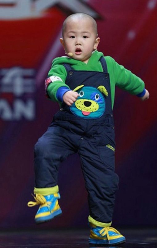 people-Toddler performing-stage-mic-Overalls with dog patch-Green hoodie-Blue and yellow shoes