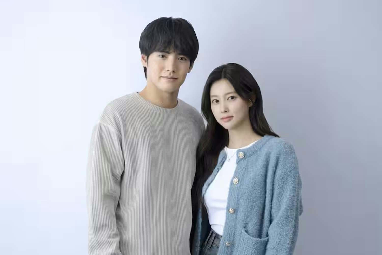 people-Two East Asian individuals (one male, one female)-A-Man wearing a light grey ribbed sweater-A-Woman wearing a light blue fuzzy cardigan and white top-A-Indoor portrait with a plain light background-A-Soft lighting-C