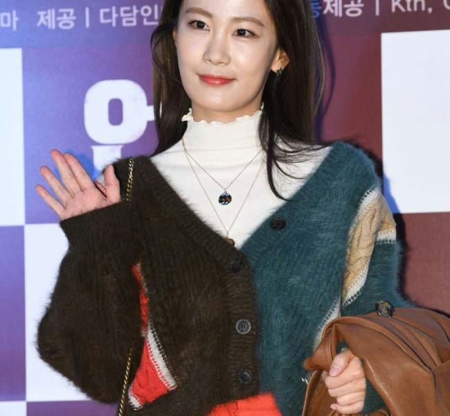 people-actress Kim So-eun-waving-brown and teal fuzzy cardigan-white turtleneck-orange pants