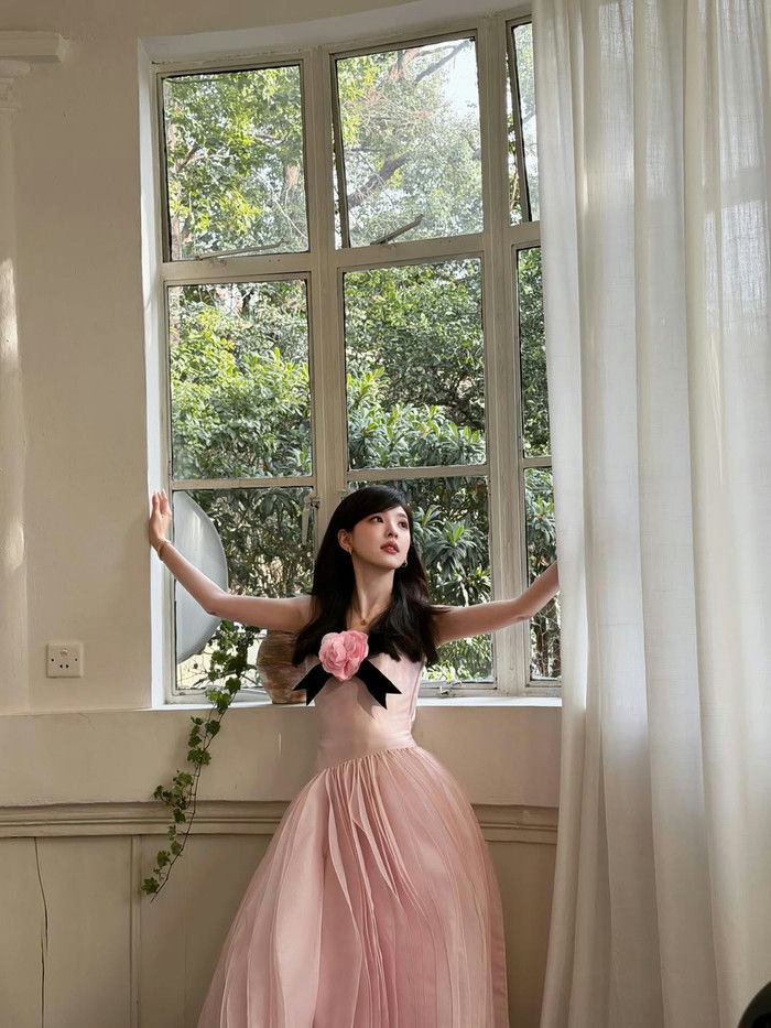 people-Korean celebrity-A-pink tulle gown-B-large pink floral embellishment-C-standing by a window with greenery visible