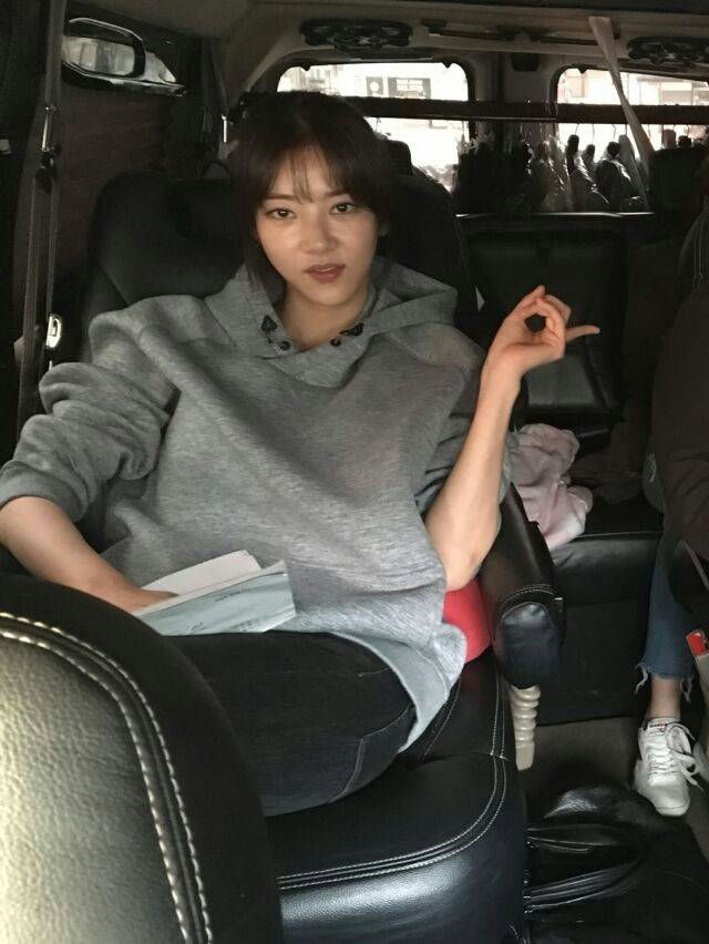 people-person in gray hoodie-sitting in vehicle-making 'OK' hand gesture-dark hair and bangs