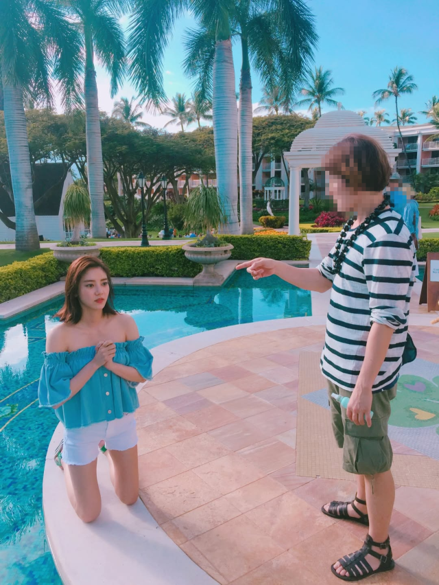 people-A-woman kneeling by a pool-A-man pointing-A-tropical resort setting-A-summer attire