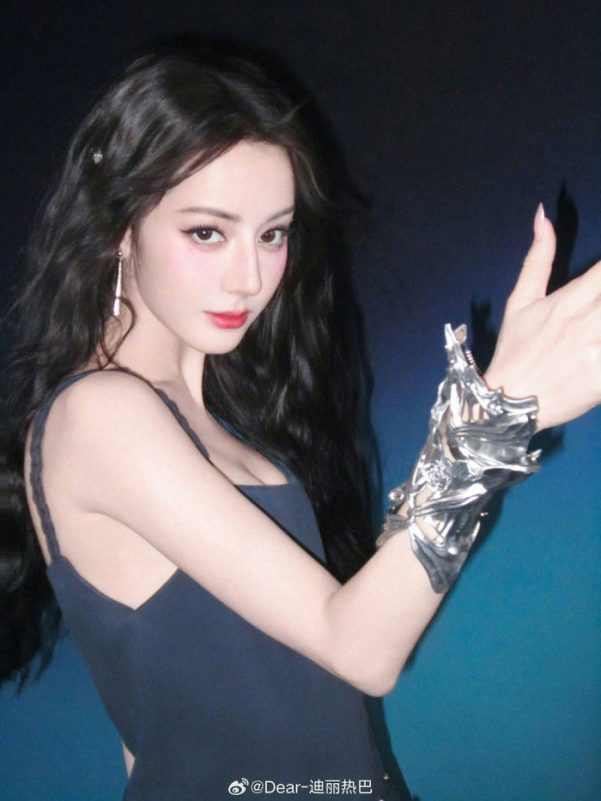 people-Dilraba Dilmurat-dark wavy hair-dark blue strap dress-silver sculptural cuff bracelet-red lipstick