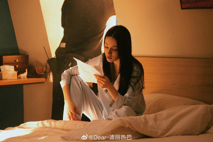 people-Dilraba Dilmurat-reading a letter-sitting on a bed-pajamas-warm lighting