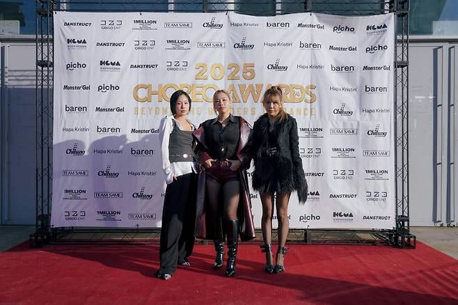 people-Three women-A-red carpet-A-sponsors backdrop-B-fashionable dark outfits-B-**2025 Choreography Awards**-C
