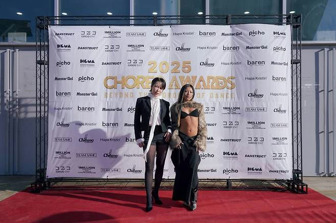 people-Two people posing on a red carpet in front of a sponsor backdrop for the 