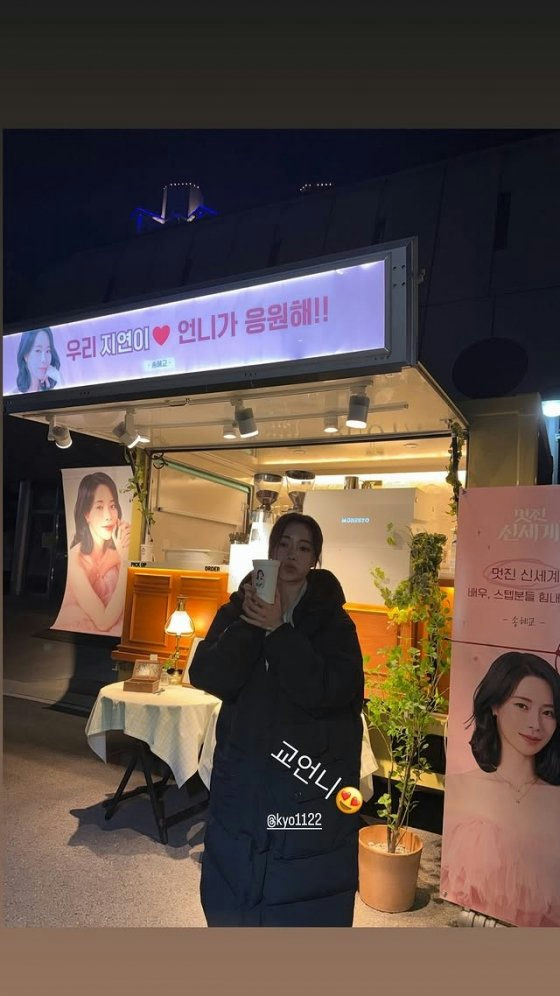 people-Person in black puffer coat holding a cup-Coffee truck support-Jiyeon (T-ara)-Support message banner-Kyo1122-Pink banner with actress photo