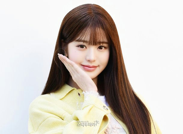 people-Jang Wonyoung-smiling-A-light yellow jacket-A-long brown hair-A-hand near face