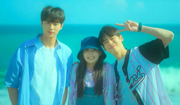 people-Three young people outdoors-A-beach or ocean background-A-Two men and one woman-A-Casual summer clothing-B-Man on left wearing blue shirt open over white t-shirt-C-Woman in center wearing bucket hat and overalls-D-Man on right flashing a peace sign