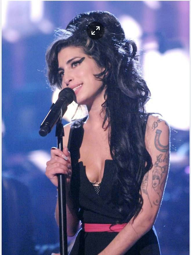 people-Amy Winehouse-A-singer-A-microphone-A-tattooed arm-A-black dress-B-stage performance-B-heavy eyeliner-C