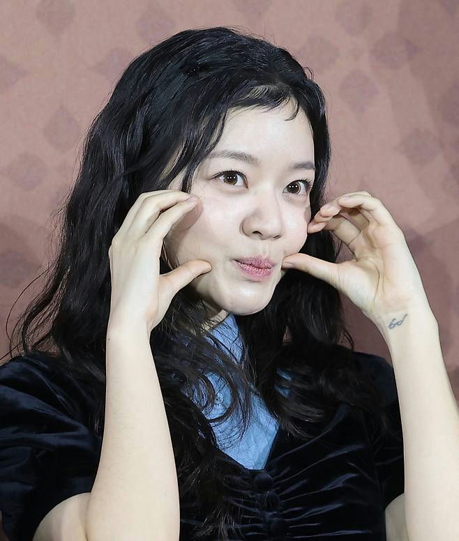 people-Go Soo-A-female-A-Asian-A-black wavy hair-A-squeezing cheeks-A-tattoo on wrist
