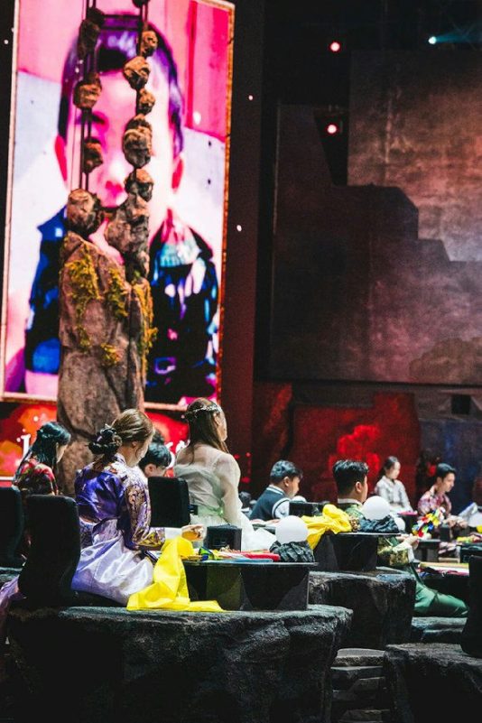 people-audience-A-traditional_attire-A-stage_performance-B-large_screen-C-dramatic_lighting