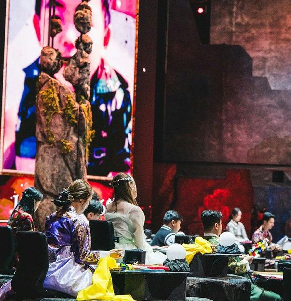 people-audience-A-traditional_attire-A-stage_performance-B-large_screen-C-dramatic_lighting