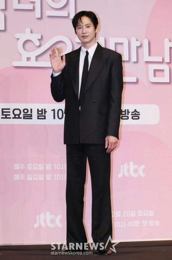 people-Lee Byung-hun-black suit-waving-standing on stage-pink background