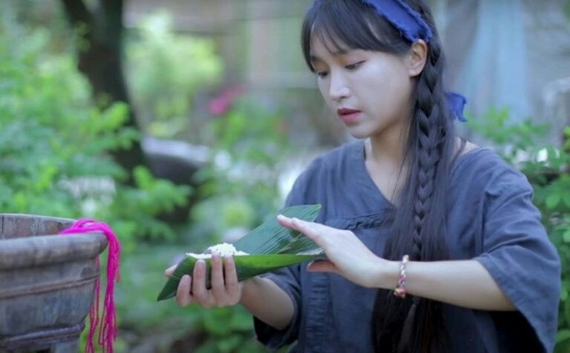 people-Chinese Woman-making Zongzi-outdoor setting-braided hair-blue headband-green foliage