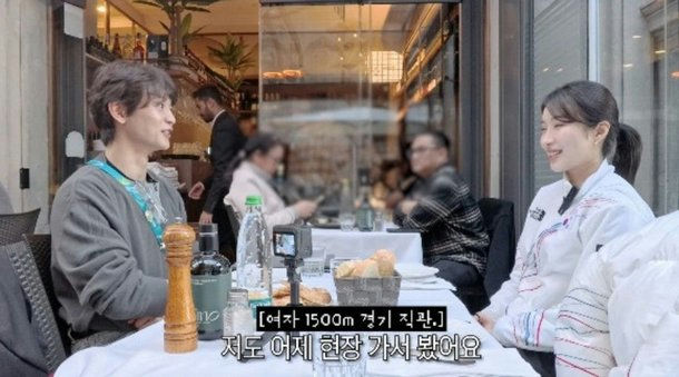 *people-Two young adults sitting at an outdoor cafe table talking-A-interview-A-Korean athletes-B-outdoor dining-B-casual conversation-C-sports event reference-C*