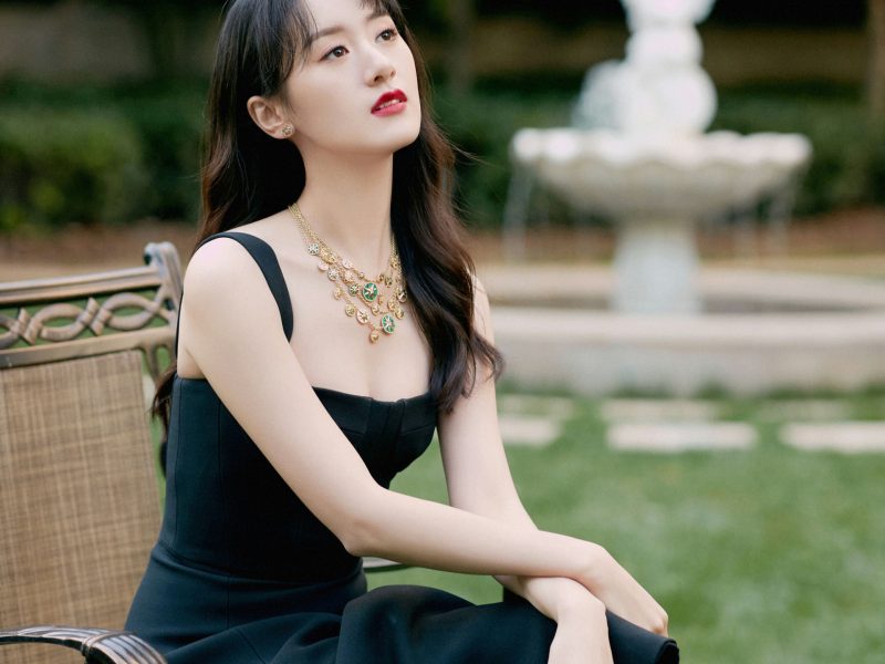 people-Zhang Jingyi-sitting outdoors-A-black dress-A-gold and green necklace-B-looking up-C-garden setting