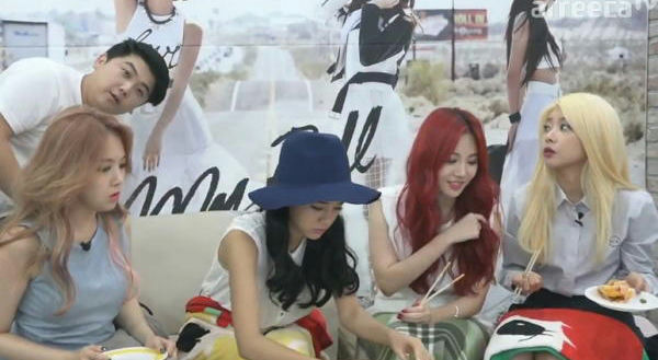 people-4 women and 1 man-sitting on a couch-wearing casual clothes-eating-A-hat-A-red hair-A-blonde hair-A-man leaning over