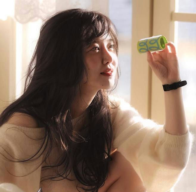 people-Young woman-A-long dark hair-A-holding green object-A-wearing cream sweater-A-looking up and right