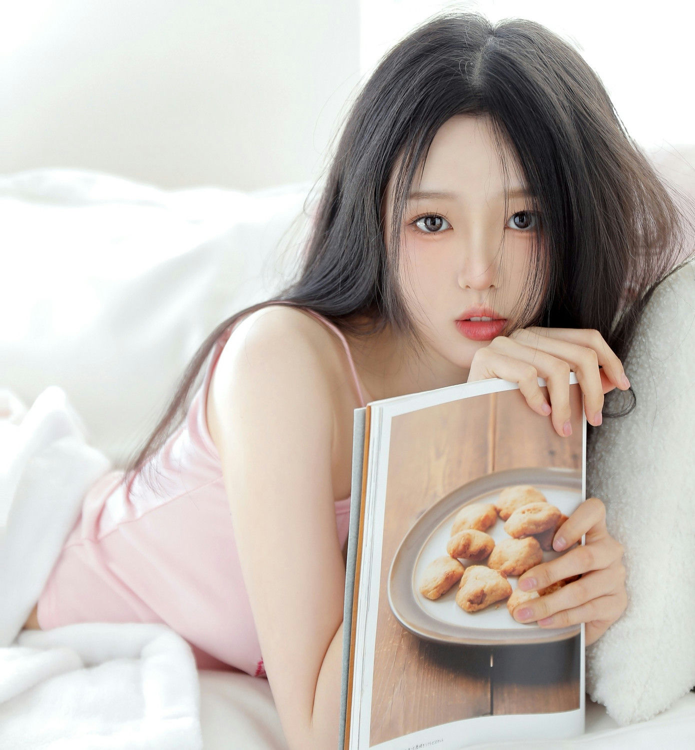 people-Asian woman-A-lying down-A-holding cookbook-A-pink tank top
