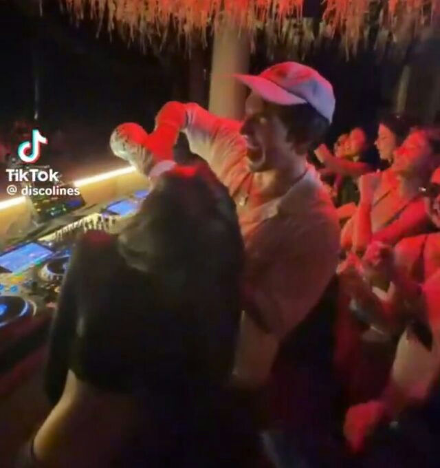 people-Young man-A-Clubbing-A-DJ booth-A-Crowd-B-Dancing-B-Smiling widely-C-Wearing a cap-C