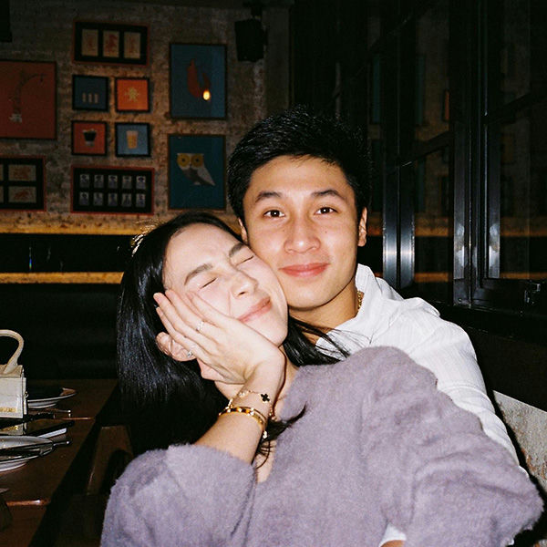 people-Asian couple-intimate moment-smiling woman-hand on cheek-man embracing-cozy restaurant setting