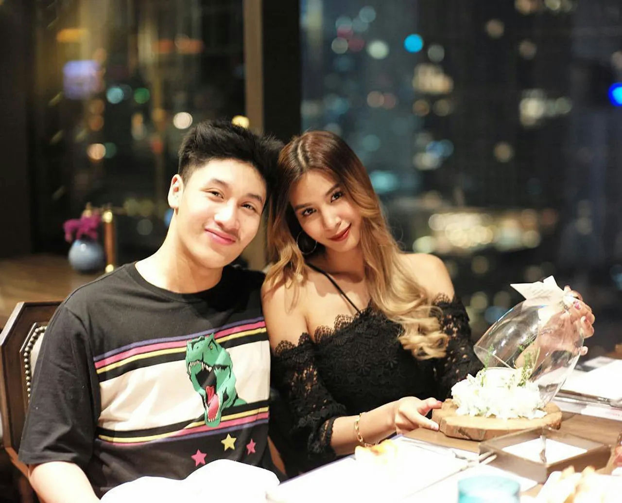 people-A-smiling couple-A-dining in a restaurant-B-night view-C-holding a small floral arrangement