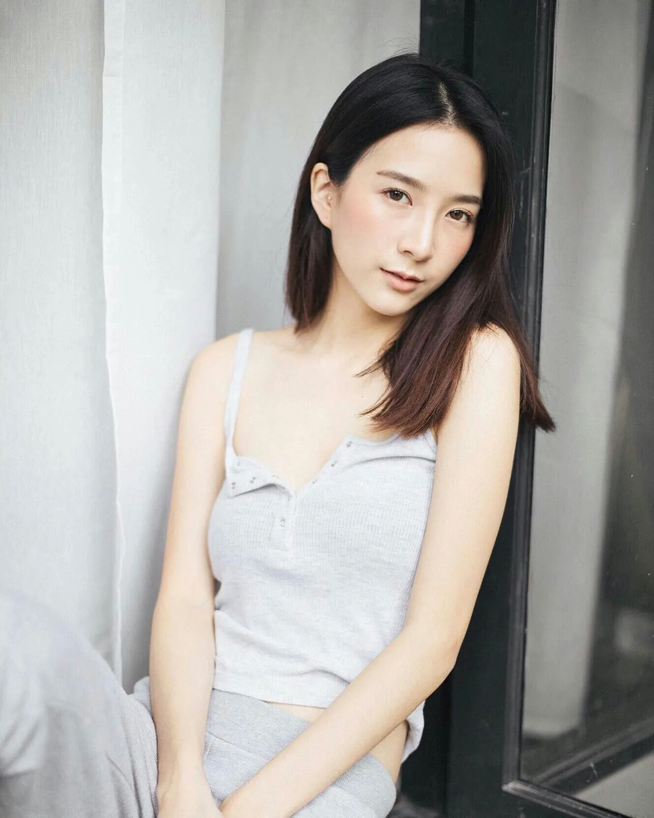 people-Asian female-A-short dark hair-A-grey ribbed tank top-A-sitting indoors-A-looking at camera