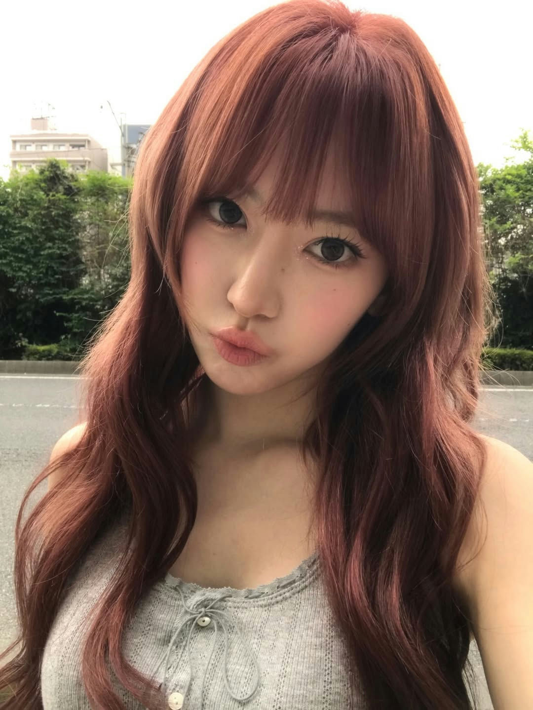 people-Young East Asian Woman-A-reddish-brown wavy hair-B-pouting lips-C-grey knitted top