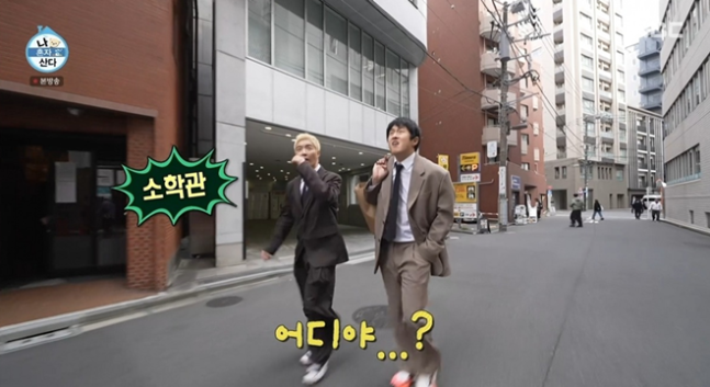 people-Two men in suits walking on a narrow city street-A-Korean variety show-B-Japanese city setting-C-Korean subtitles