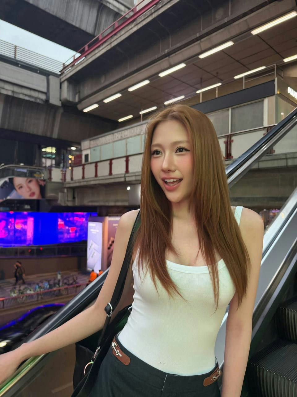 people-woman-long brown hair-white tank top-on escalator-urban background