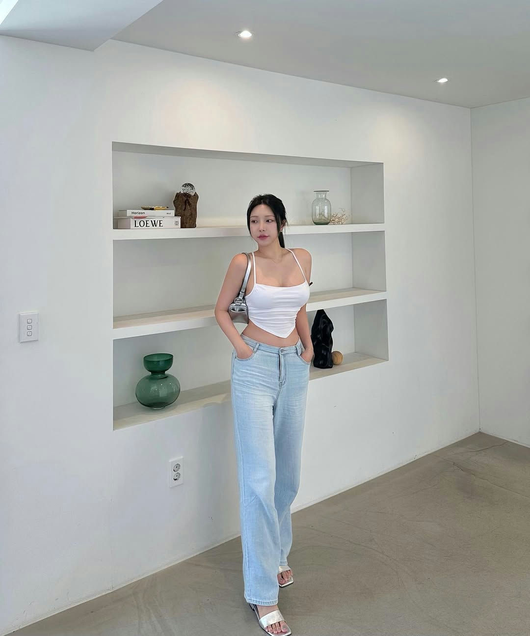 people-Woman-A-white crop top-A-light wash wide-leg jeans-A-silver sandals-A-white built-in shelving-A-minimalist interior