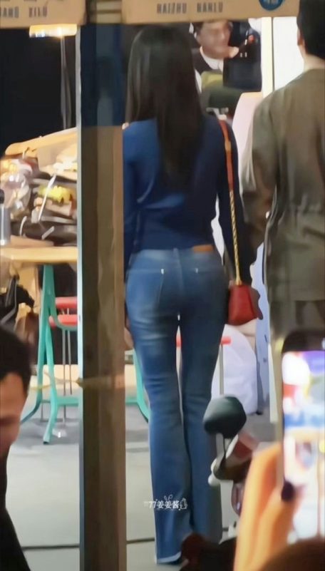 people-Woman in blue top and jeans-A-Long dark hair-A-Red shoulder bag-B-Flared blue jeans-C-Seen from behind