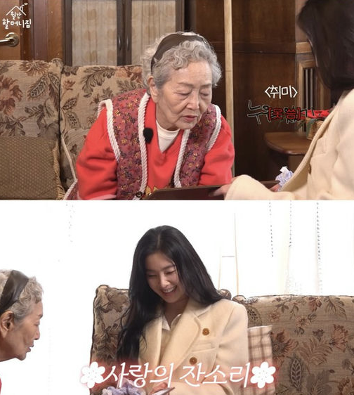 people-an elderly Korean woman-a younger Korean woman (likely a celebrity/host)-Korean television program-Two people indoors-seating on patterned sofas-warm lighting