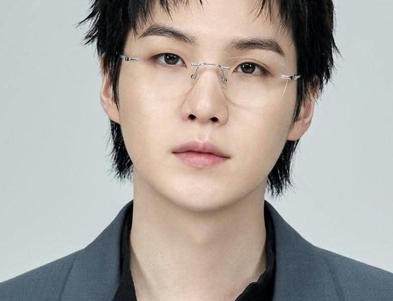 people-Suga (Min Yoongi)-rimless glasses-black messy hair-grey blazer-black shirt-gold chain