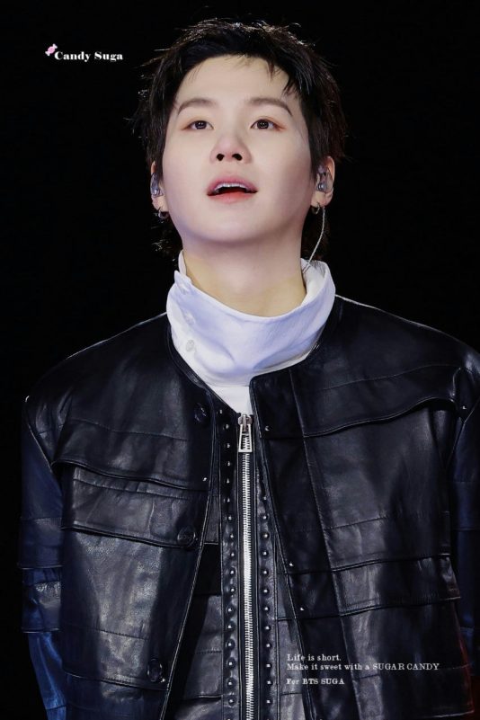 people-Suga (Min Yoongi) of BTS-Close-up performance shot-Black leather jacket-White turtleneck-Dark background