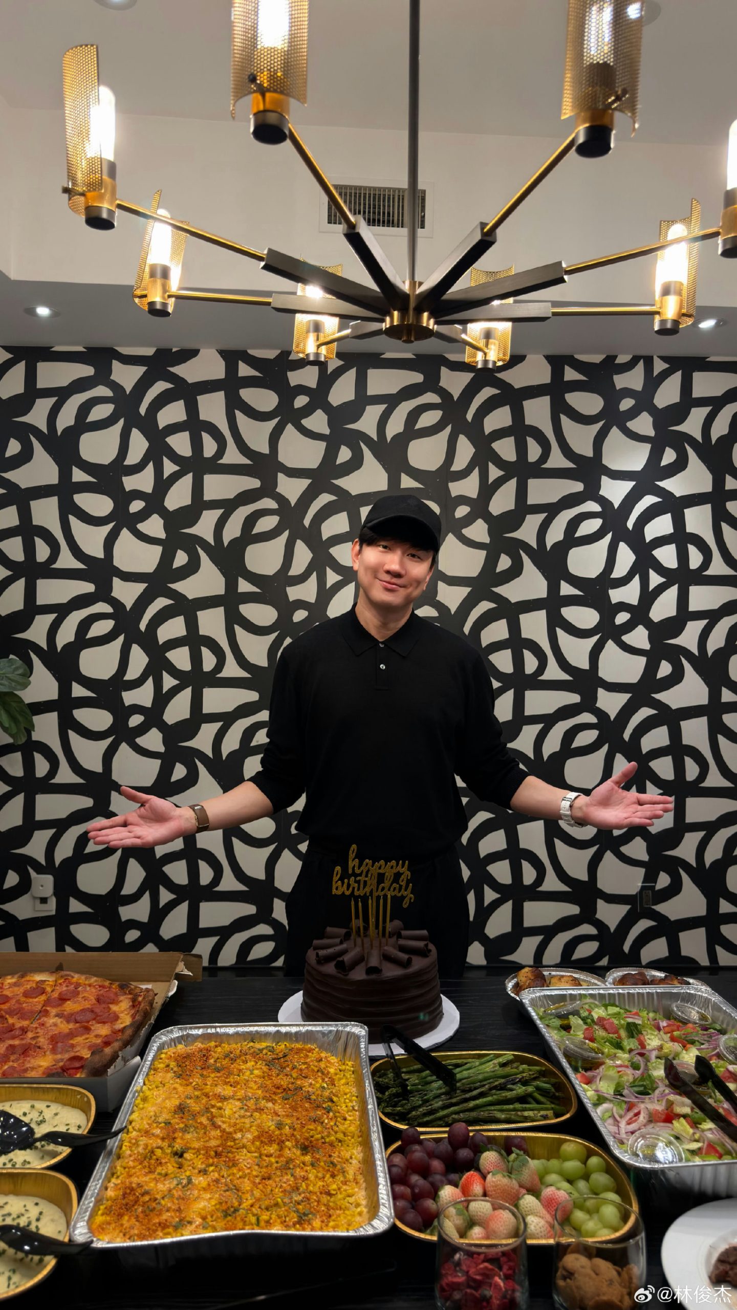 people-JJ Lin-birthday celebration-posing in front of food-black and white wall mural-gold chandelier