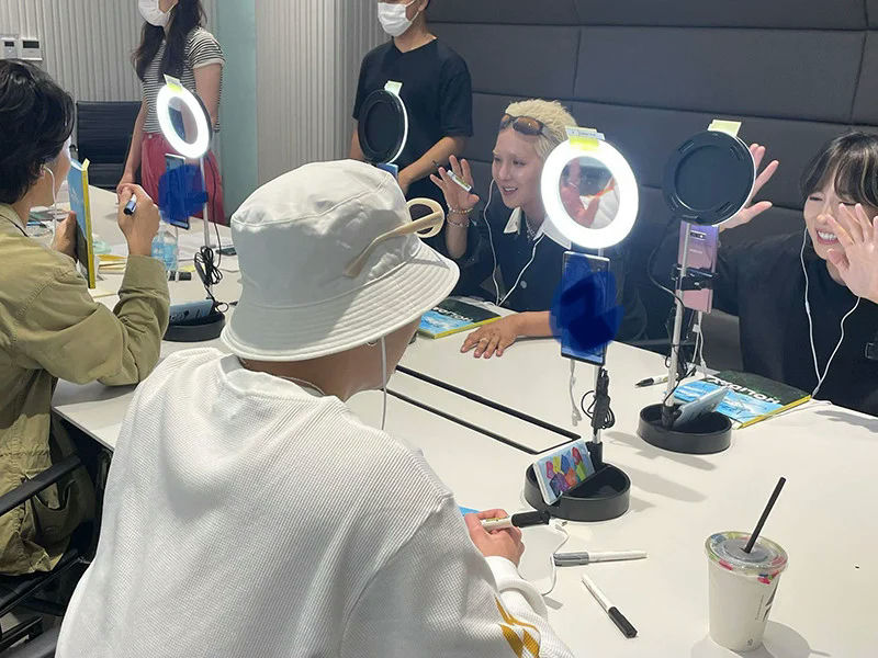 people-four people indoors-A-livestreaming setup-A-ring light-B-smartphone-B-white bucket hat-C-happy expression