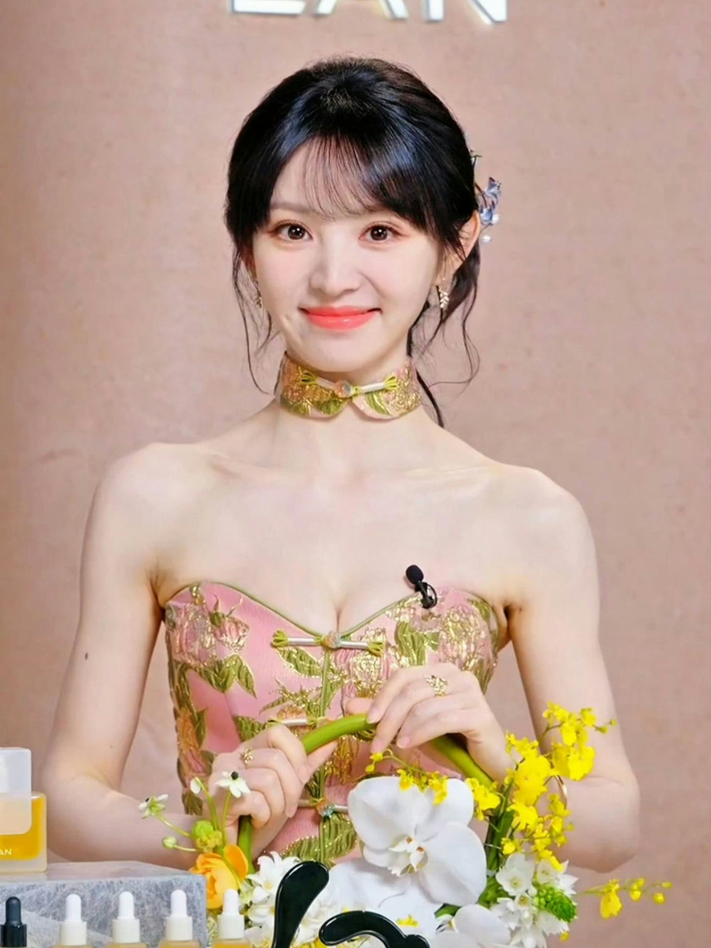people-Zhou Jiefu-strapless pink and gold floral top-A-green and gold floral choker-B-holding green stem and yellow/white flowers-C